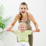 Mother mother holding baby sitting on fitness ball