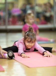 5 year old little girl practices a straddle split during a floor exercise at a gym on the mat (stretching)